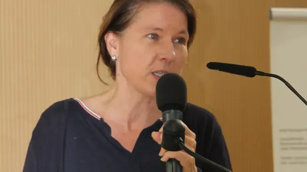 Das Bild zeigt Dr. Natascha Sommer während einer Rede. Sie steht an einem Rednerpult und spricht in ein Mikrofon. Im Hintergrund sind das Logo der Rene Baumgart Stiftung und weitere Informationstafeln sichtbar.