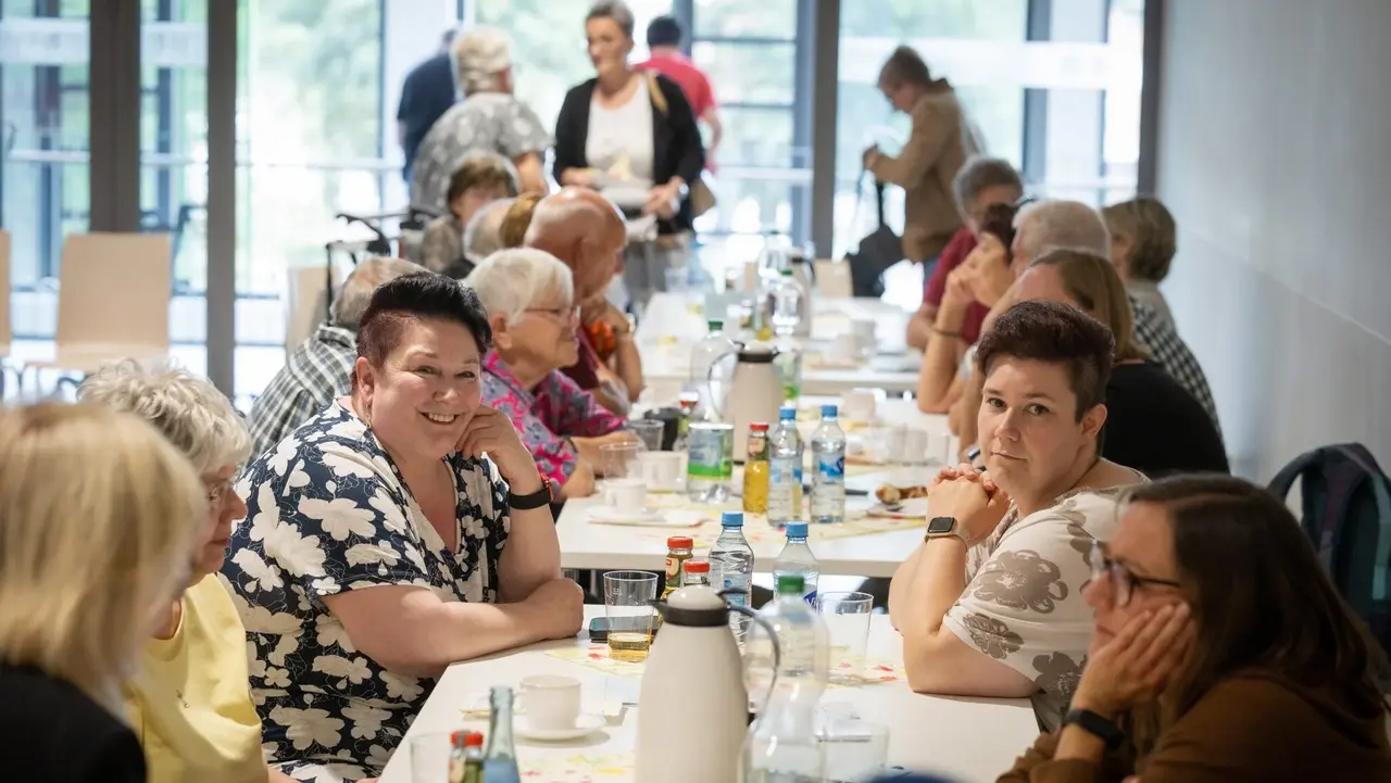 Menschen sitzen an einem Tisch und unterhalten sich. 