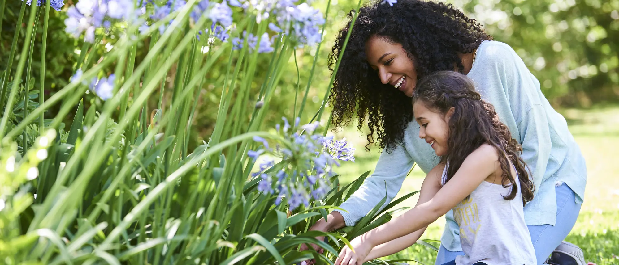 Mother and daughter planting flowers in garden